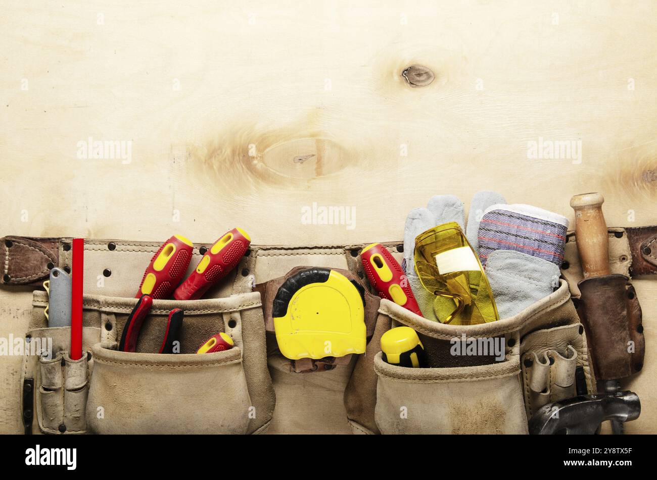 Werkzeuggürtel mit Tischlerwerkzeugen und Schutzverschleiß auf Sperrholz Flachblattansicht des Blatts Stockfoto