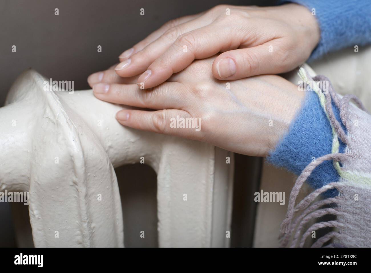 Eine weiße Frau hält ihre Hände am Heißwasserstrahler. Heizungskonzept. Leerzeichen für Text Stockfoto Eine weiße Frau hält ihre Hände am Heißwasserstrahler. Heizungskonzept. Leerzeichen für Text Stockfoto