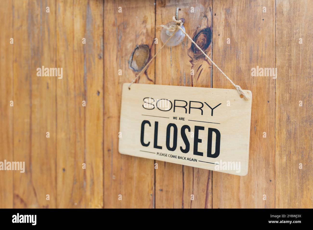 Nahaufnahme eines geschlossenen Ladenschildes vor Holzhintergrund Stockfoto