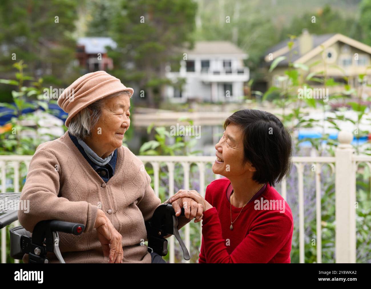 Eine ältere Frau sitzt auf dem Gehhilfen. Eine schöne Zeit mit ihrer Tochter zu Hause im Garten. Stockfoto
