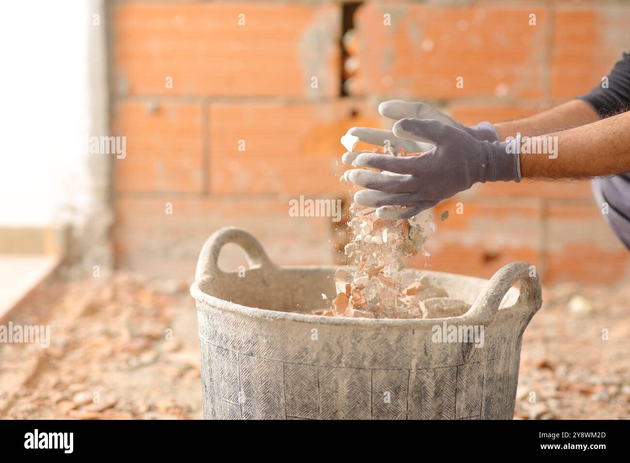 Nahaufnahme eines Bauarbeiters Hände, die in einem Haus, das gerade reformiert wird, die Wanne mit Trümmern füllen Stockfoto