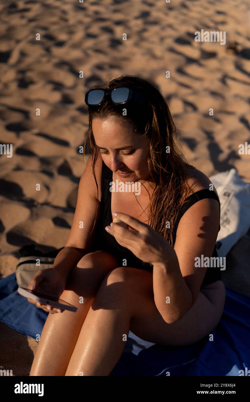 Eine Frau benutzt ein Smartphone am Strand am Strand. Stockfoto