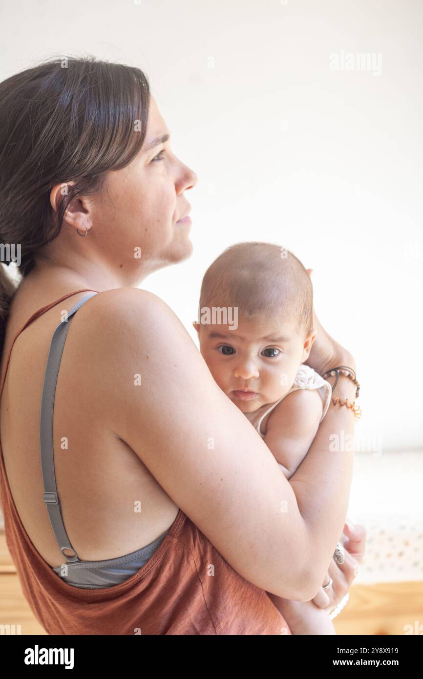 Eine Frau hält ein Baby in den Armen in einer entspannten und nachdenklichen Pose. Das Baby ist ruhig. Stockfoto