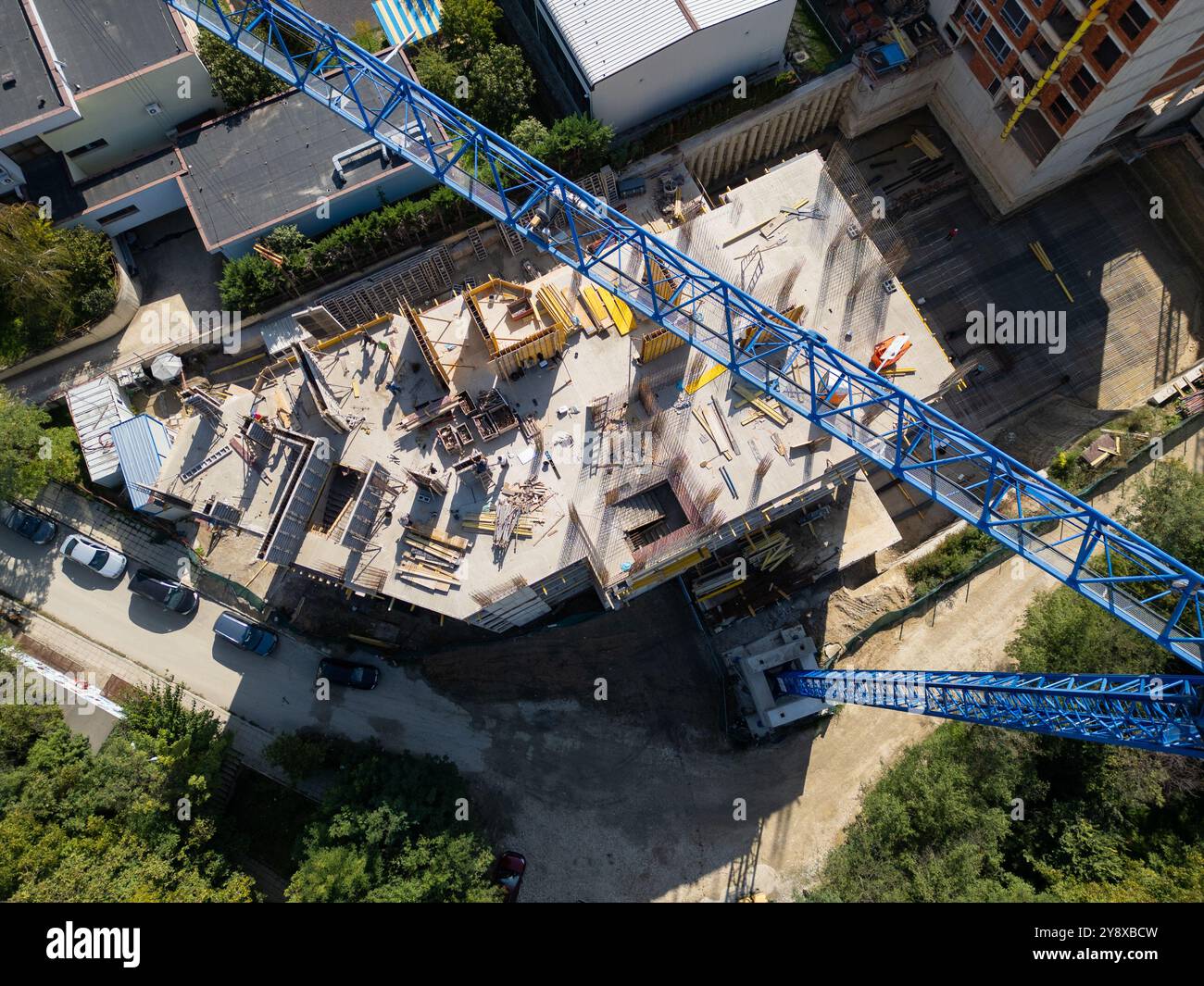 Luftdrohnenvideo einer Baustelle mit einem Kran und nahe gelegenen Wohngebäuden. Das Filmmaterial erfasst den Fortschritt der Stadtentwicklung, Surro Stockfoto