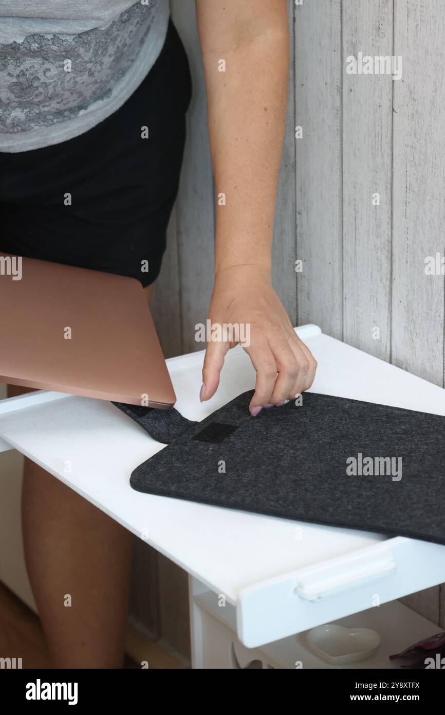 Eine Frau legt einen Laptop in eine Filzhülle. Stockfoto