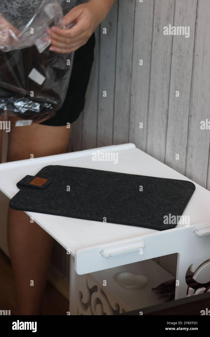 Eine Frau demonstriert eine Laptop-Hülle. Das Gehäuse besteht aus Filz. Stockfoto