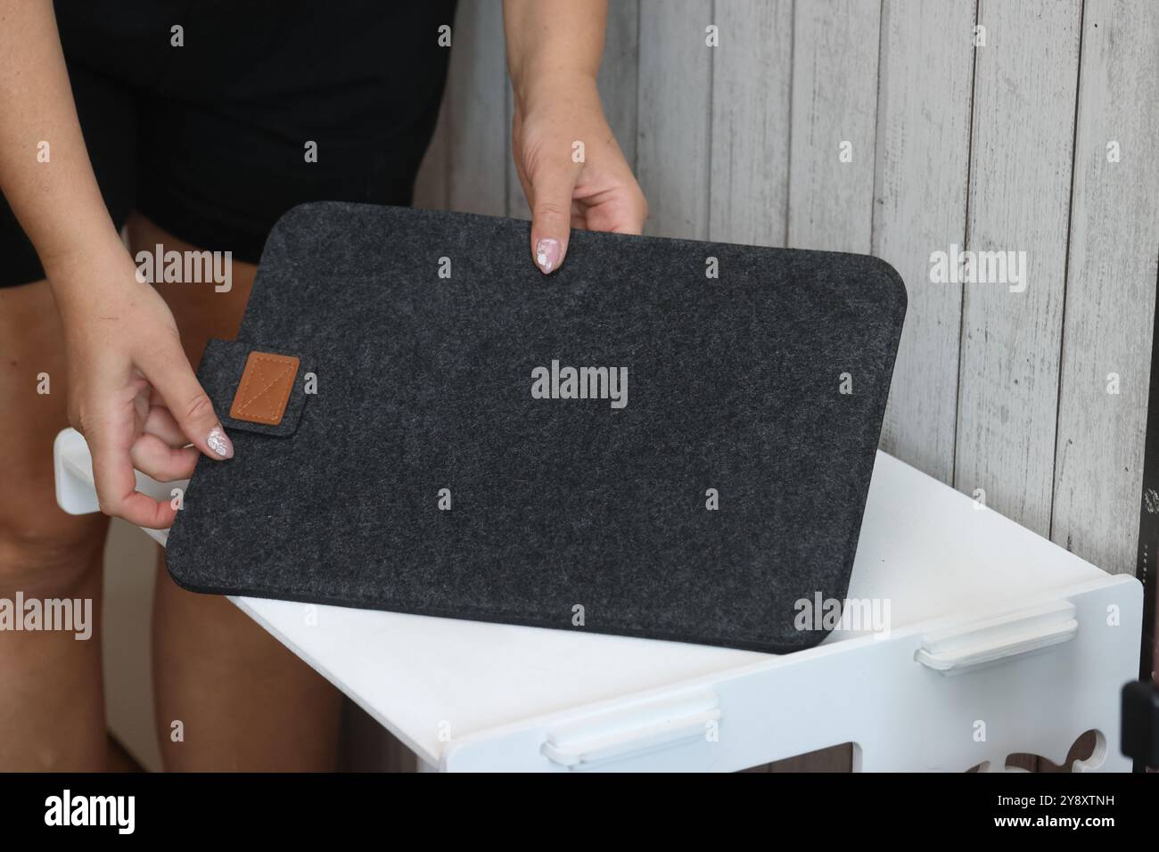Eine Frau demonstriert eine Laptop-Hülle. Das Gehäuse besteht aus Filz. Stockfoto