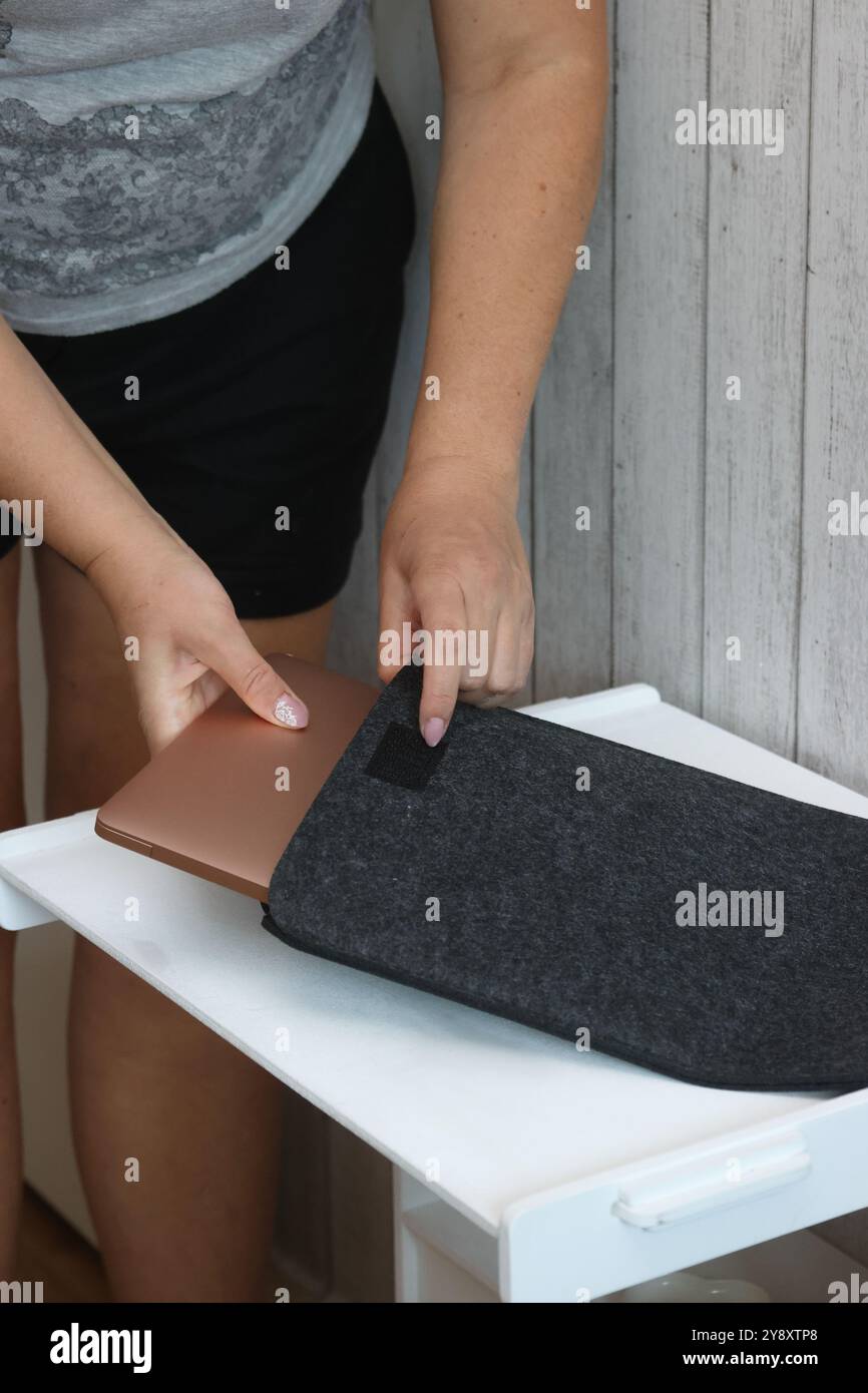 Eine Frau legt einen Laptop in eine Filzhülle. Stockfoto