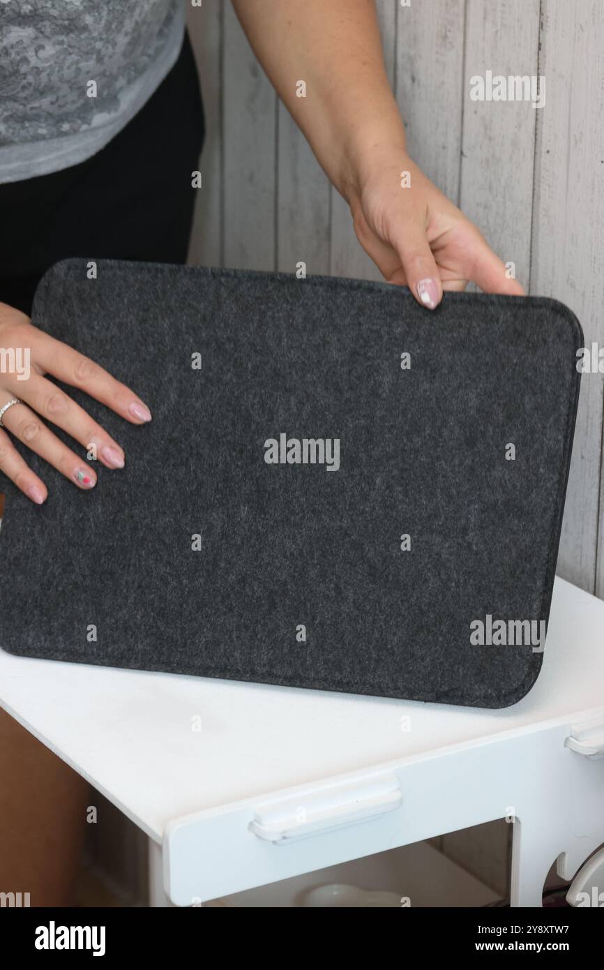Eine Frau demonstriert eine Laptop-Hülle. Das Gehäuse besteht aus Filz. Stockfoto