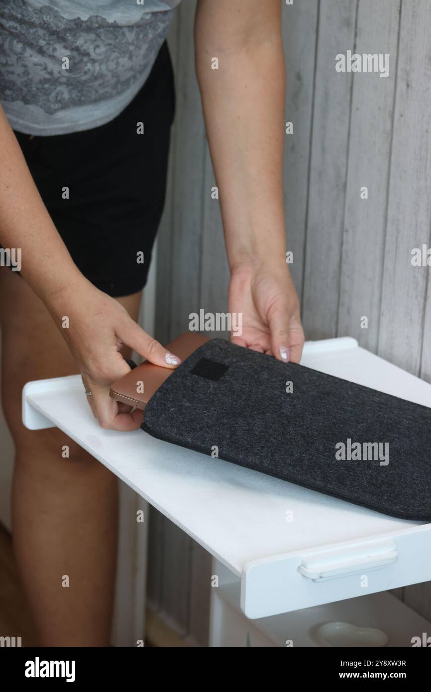 Eine Frau legt einen Laptop in eine Filzhülle. Stockfoto