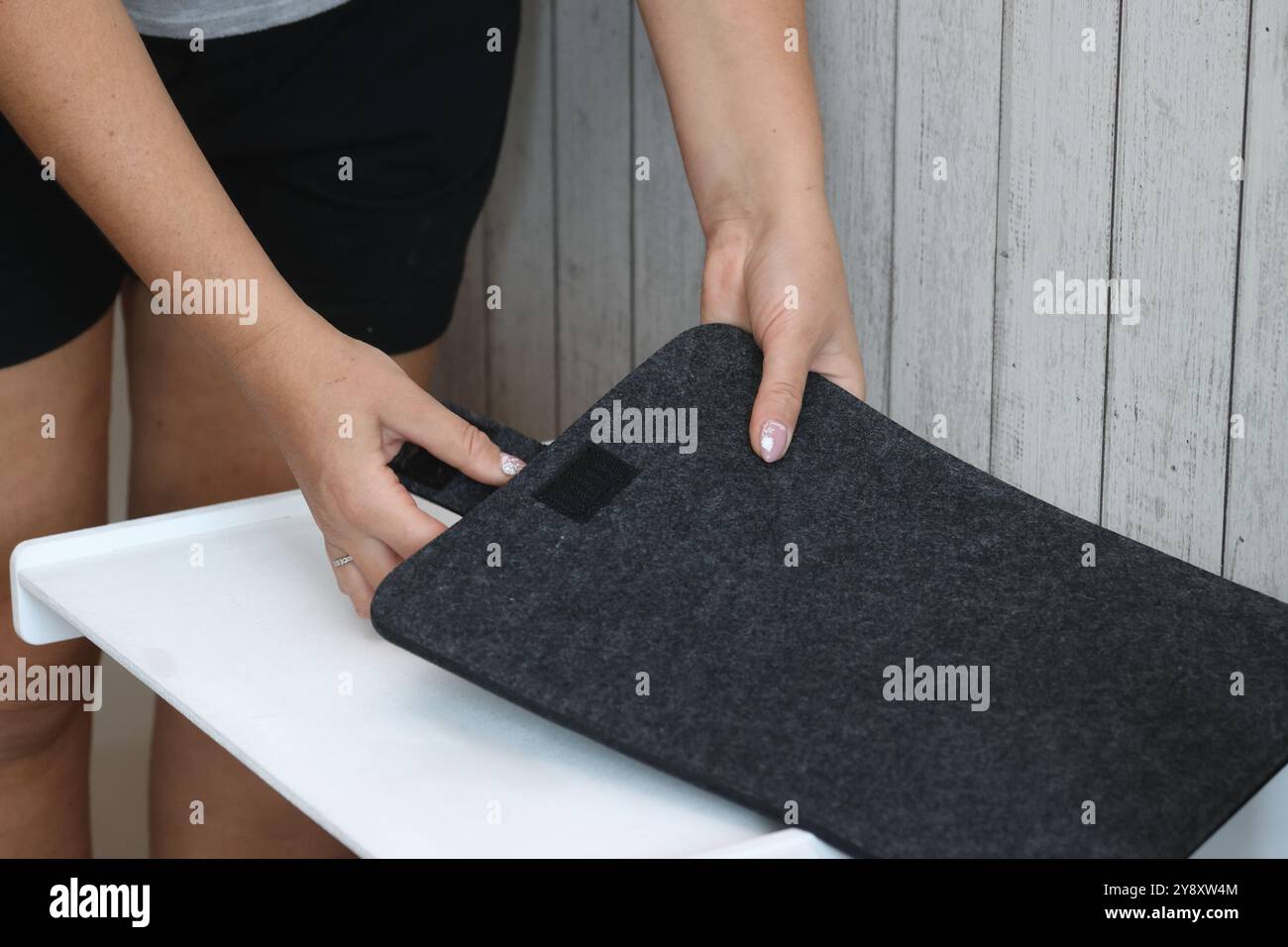 Eine Frau demonstriert eine Laptop-Hülle. Das Gehäuse besteht aus Filz. Stockfoto