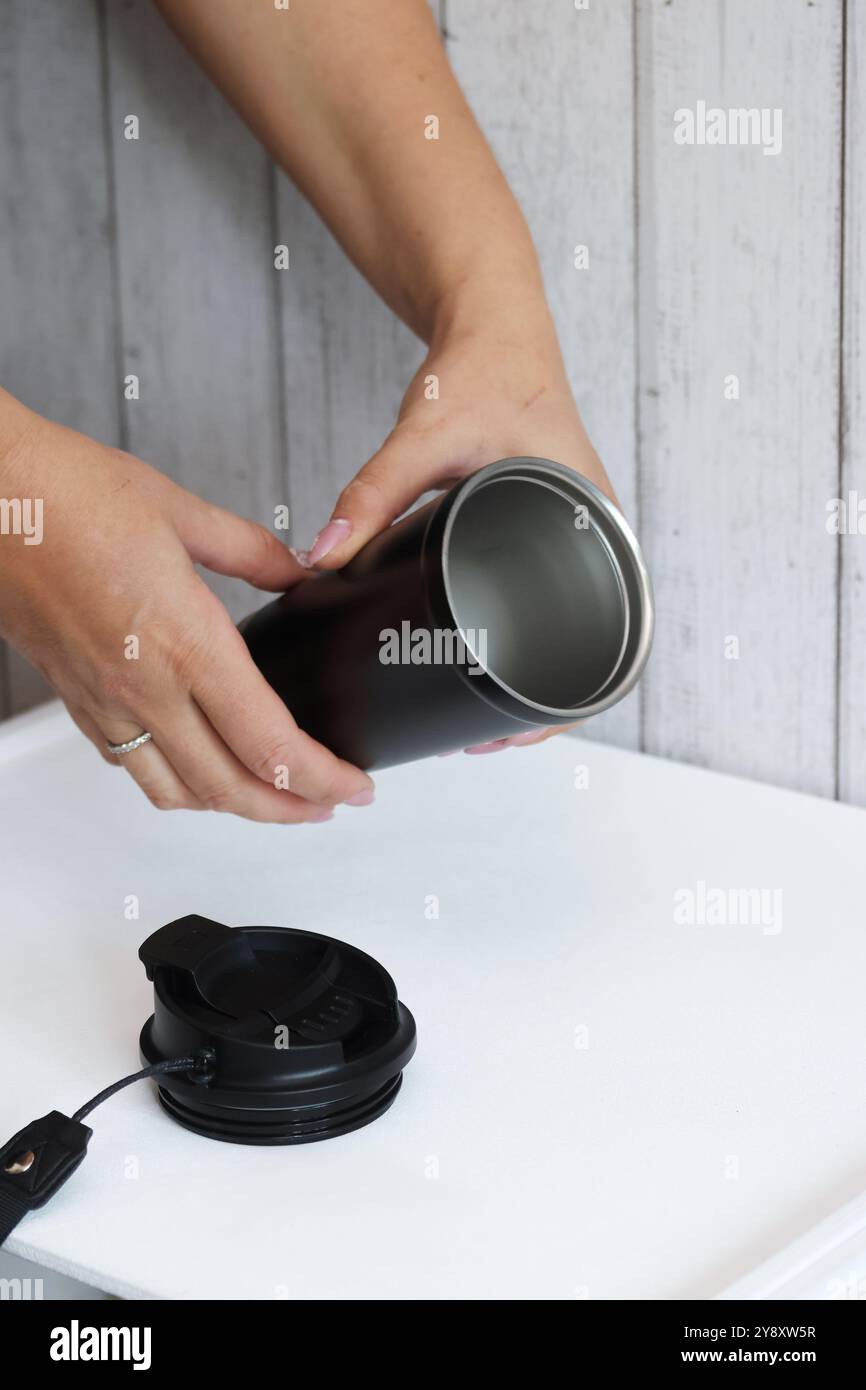 Eine Frau prüft einen Kauf auf einem Marktplatz. Sie demonstriert einen Thermosbecher. Stockfoto