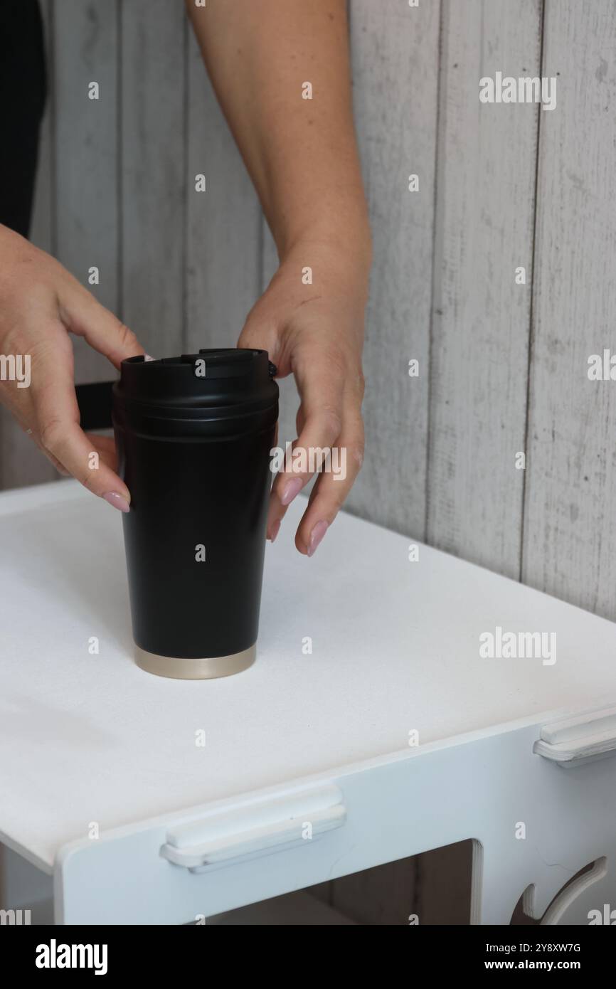 Eine Frau prüft einen Kauf auf einem Marktplatz. Sie demonstriert einen Thermosbecher. Stockfoto