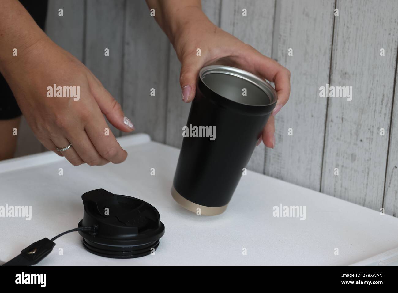 Eine Frau prüft einen Kauf auf einem Marktplatz. Sie demonstriert einen Thermosbecher. Stockfoto