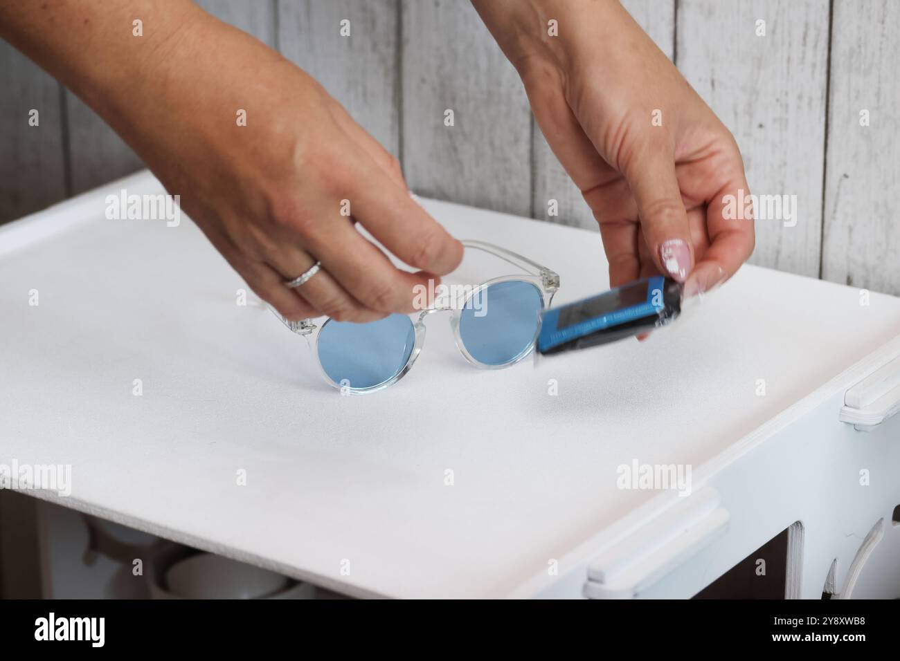 Eine Frau überprüft die Polarisation einer Sonnenbrille mit blauen Gläsern. Sie prüft einen Kauf auf einer Marketplace-Site. Vertikales Video. Stockfoto