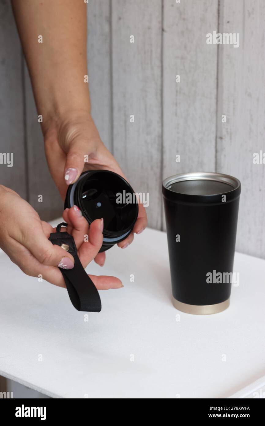 Eine Frau prüft einen Kauf auf einem Marktplatz. Sie demonstriert einen Thermosbecher. Stockfoto