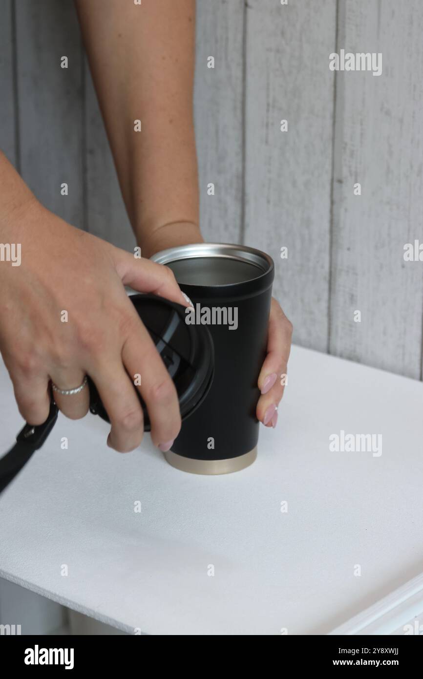 Eine Frau prüft einen Kauf auf einem Marktplatz. Sie demonstriert einen Thermosbecher. Stockfoto