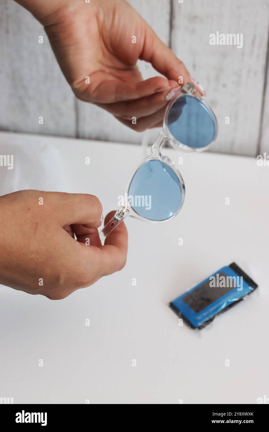 Eine Frau zeigt eine Sonnenbrille für Damen mit blauen Gläsern. Sie prüft einen Kauf auf einer Marketplace-Site. Stockfoto