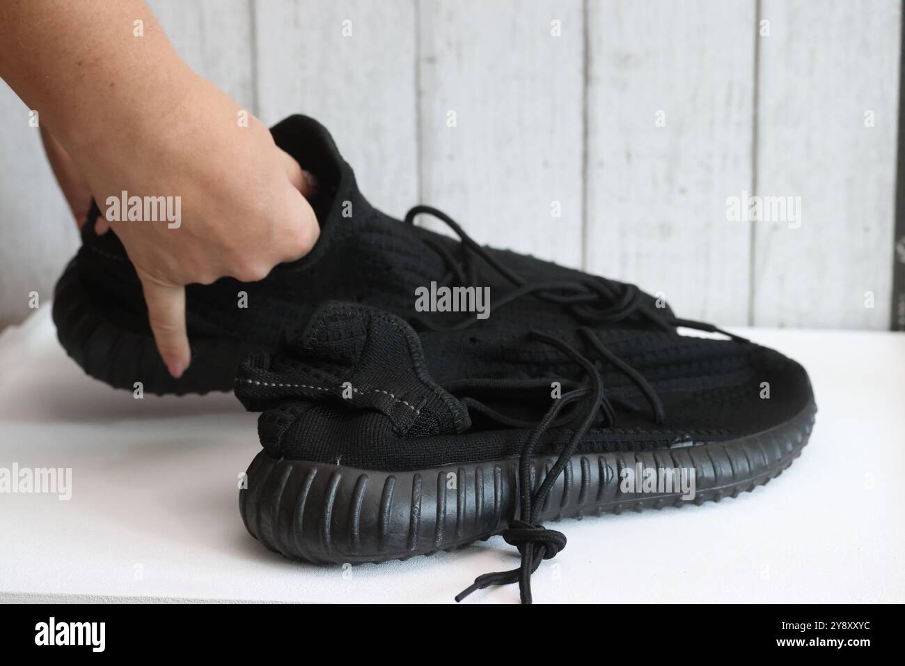 Eine Frau überprüft schwarze Sneakers. Demonstration eines auf einer Marketplace-Site getätigten Kaufs. Stockfoto