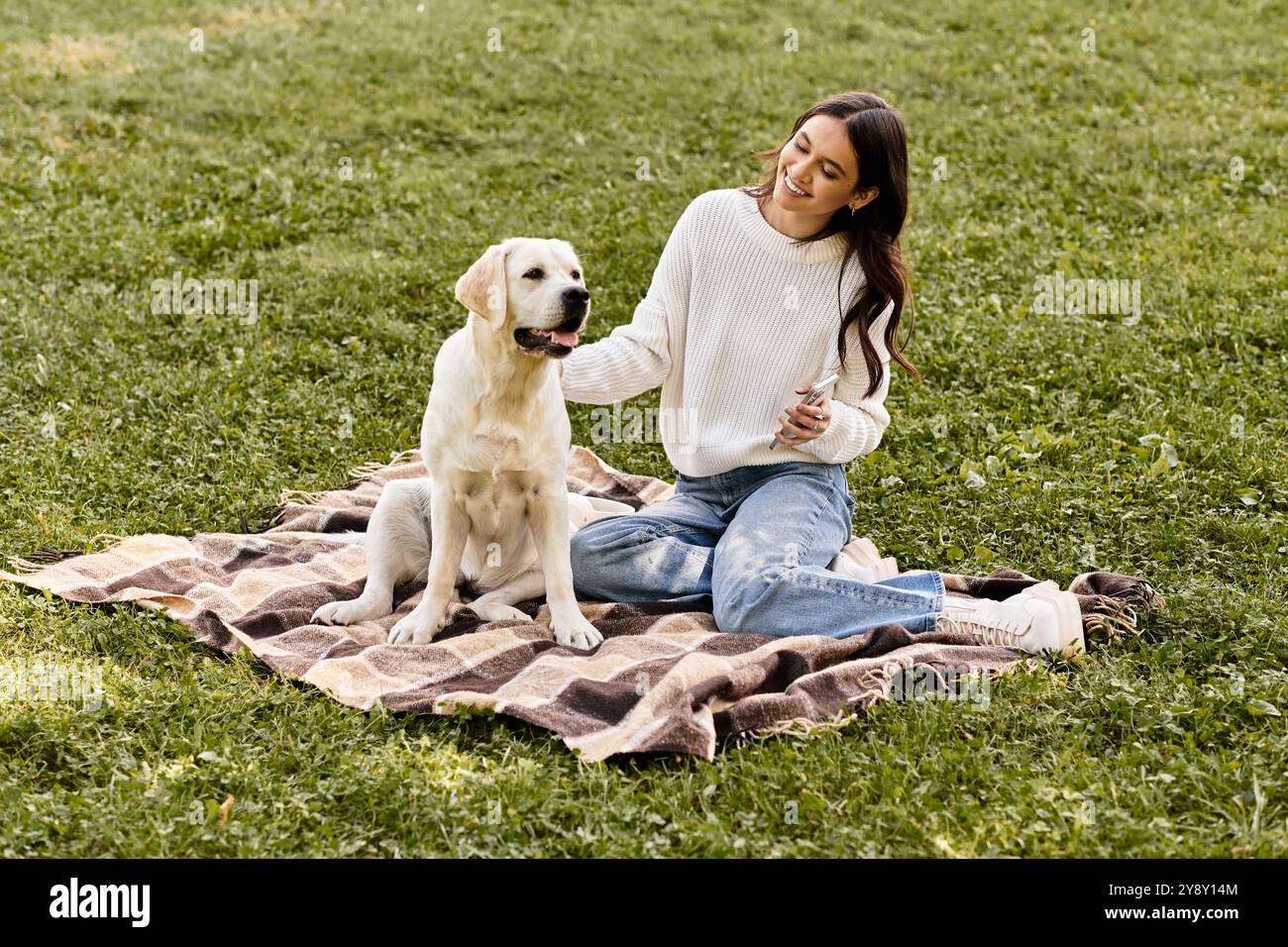 Eine junge Frau genießt die Gesellschaft ihres Hundes auf einer gemütlichen Decke, umgeben von Herbstlaub. Stockfoto