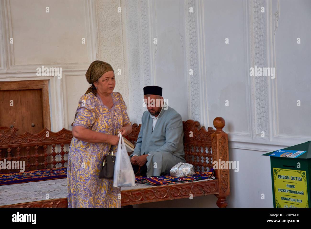 Samarkand, Usbekistan; 18. September 2024: Eine muslimische Frau, die nach dem Gebet neben einem Imam in der historischen Stadt Samarkand, Usbekistan, aufsteht. Stockfoto