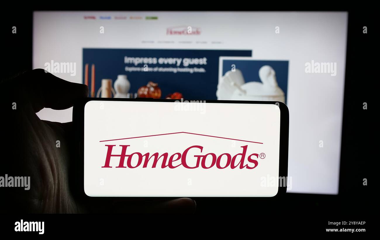 Person, die ein Mobiltelefon mit dem Logo des US-amerikanischen Einrichtungsunternehmens HomeGoods auf dem Bildschirm vor der Business-Website hält. Schwerpunkt auf dem Display des Telefons. Stockfoto