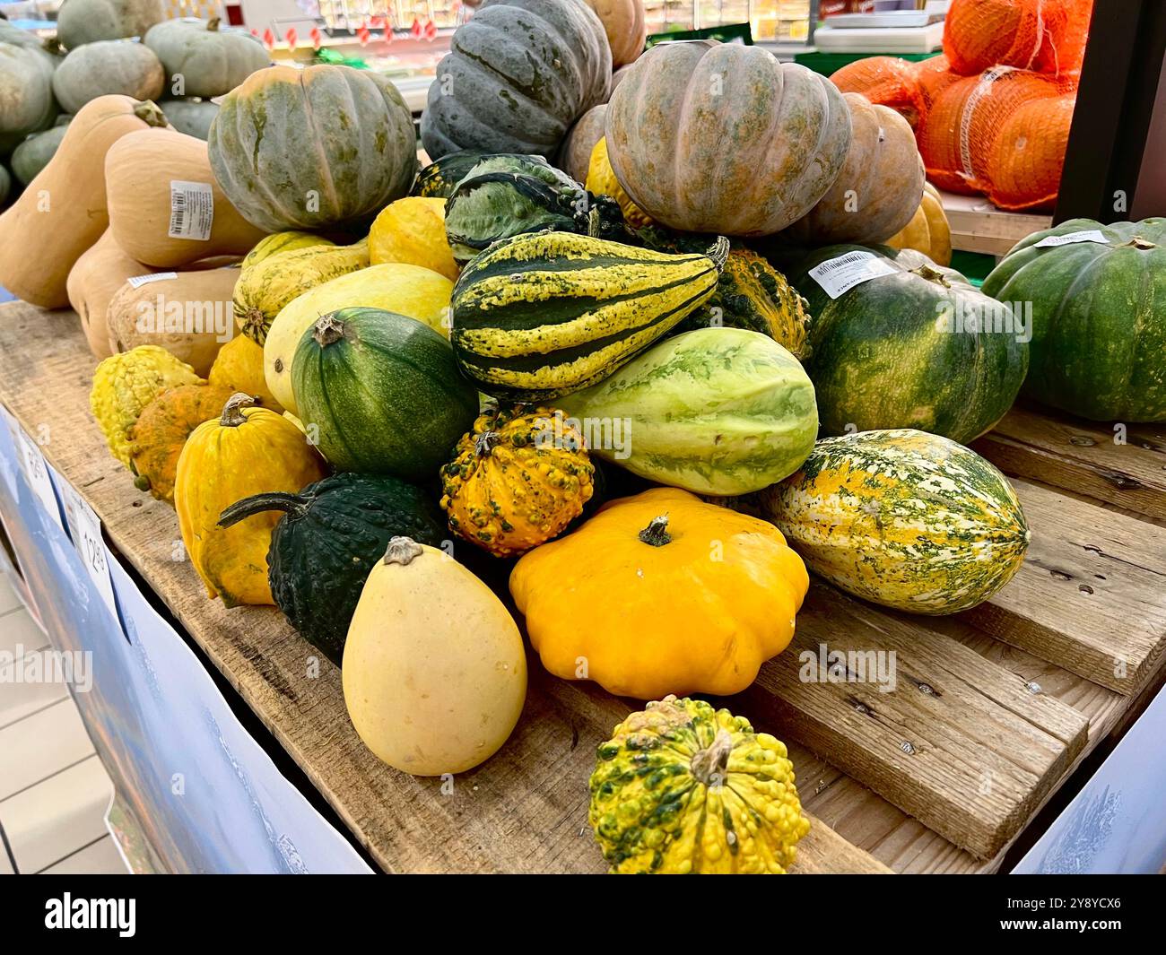 Farbenfrohe Kürbisse auf einem Ladentisch mit lebhaften Herbstprodukten. Perfekt für herbstliche Themen, saisonale Einkäufe, Ernte und festliche Einrichtung - Smartphone-aufgenommenes Stockfoto