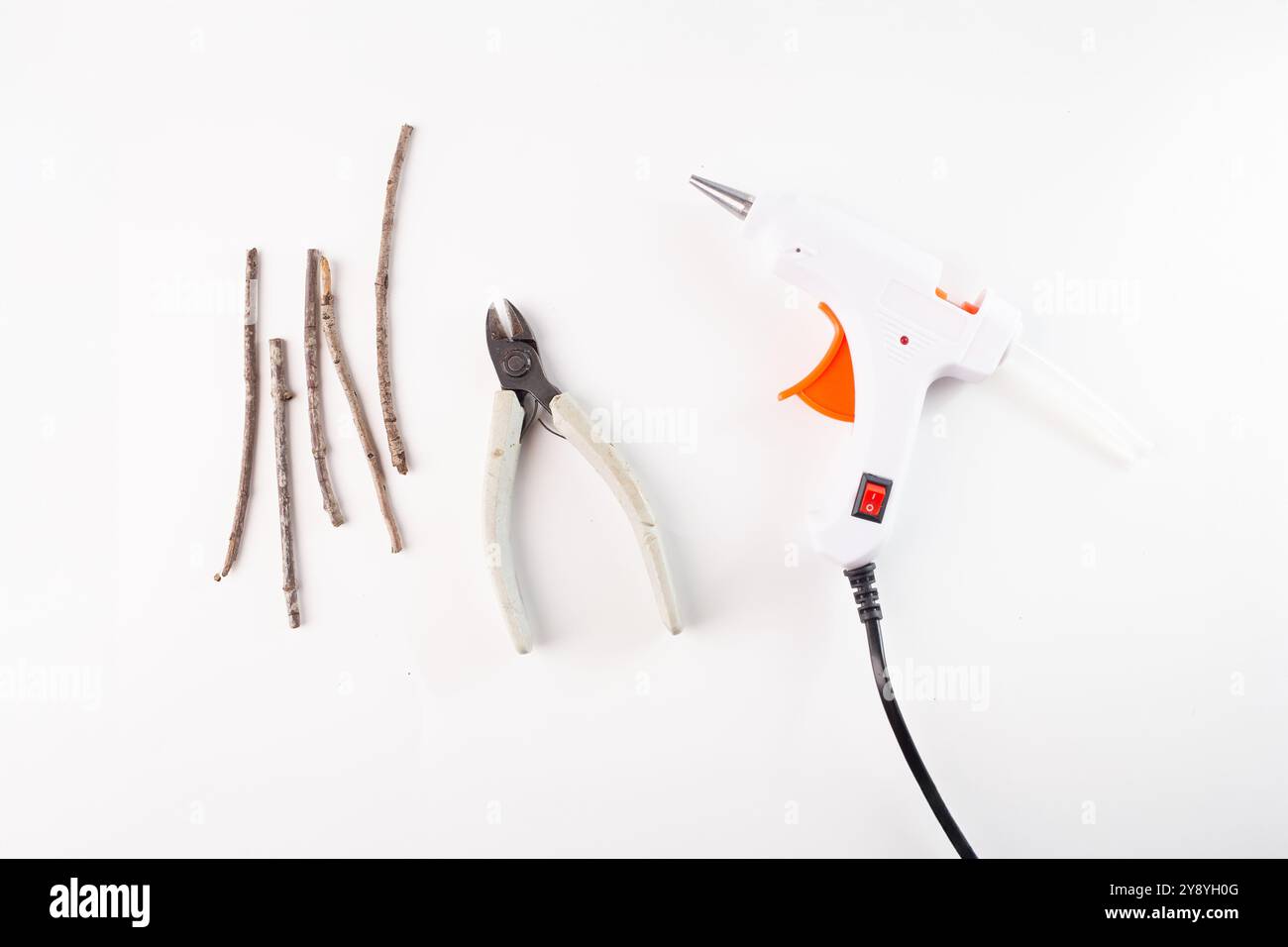 Sammlung von kleinen Stäben, einer Zange in der Mitte und einer Klebepistole auf der rechten Seite. Bastelprojekte oder Heimwerkerprojekte, Stockfoto