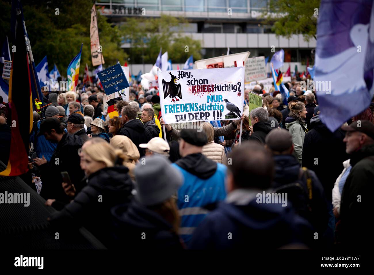 Friedensdemo Nein zu Kriegen DEU, Deutschland, Deutschland, Berlin, 03.10.2024 Demonstranten mit Schild Hey schon Kriegstuechtig nur Friedenssuechtig du Depp auf der bundesweiten Demonstration der deutschen Friedensbewegung unter dem Motto Nein zu Kriegen und Hochruestung die Waffen nie Ja zu Frieden und soziale Friedenspolitik in Berlin Deutschland . Der Protest verschiedene Initiativen und Parteien wie Buendnis Bündnis BSW Sahra Wagenknecht , SPD, die linke , Gewerkschaften etc. Fordert einen Waffenstillstand in Gaza und Nahost , Friedensverhandlungen sowie Ende der Sanktionen und den Krieg U Stockfoto