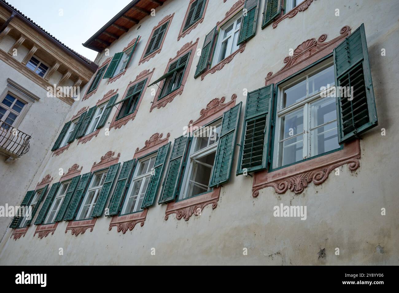 Ein Gebäude mit alten grünen Fensterläden und braunen Stuckfenstern, Meran, Norditalien. Stockfoto