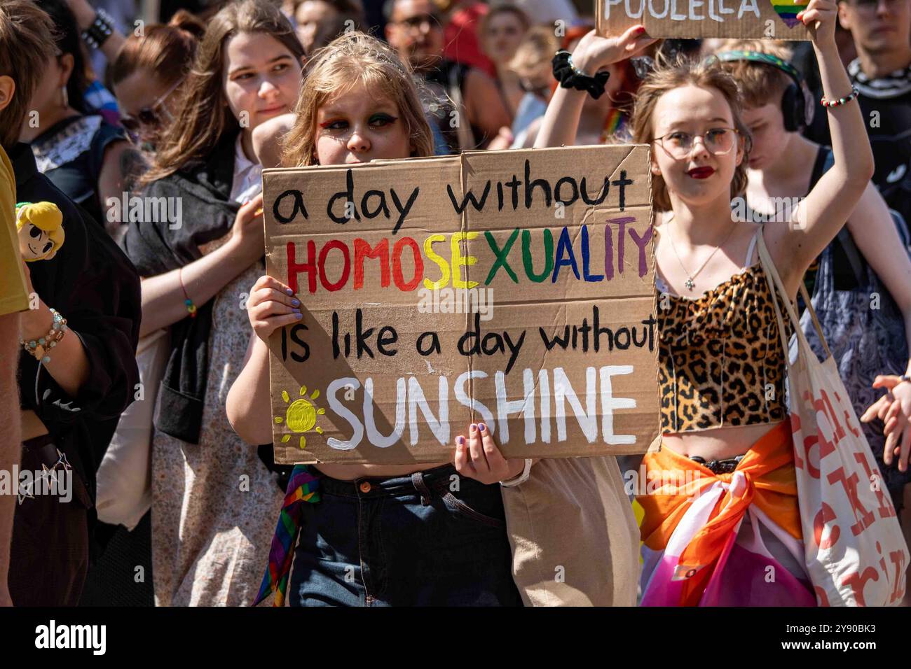 Ein Tag ohne Homosexualität ist wie ein Tag ohne Sonnenschein. Junge Frau mit einem Pappschild bei der Helsinki Pride 2024 Parade in Helsinki, Finnland. Stockfoto