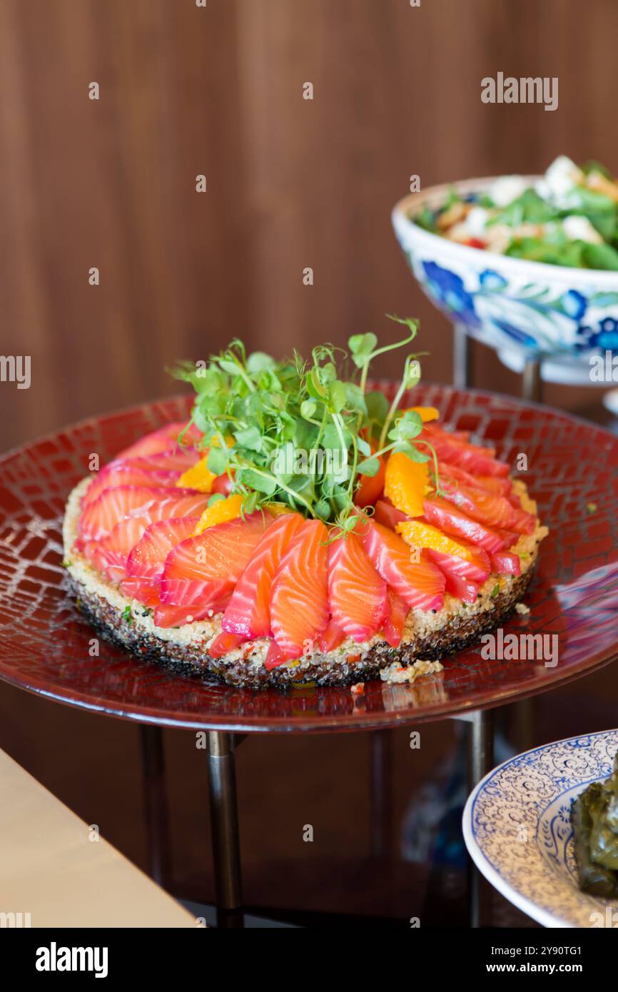 Ein Teller mit frischem Lachs und Orangensalat mit Gourmet-Touch. Das Gericht ist bunt und nahrhaft, perfekt für eine leichte, gesunde Mahlzeit. Stockfoto