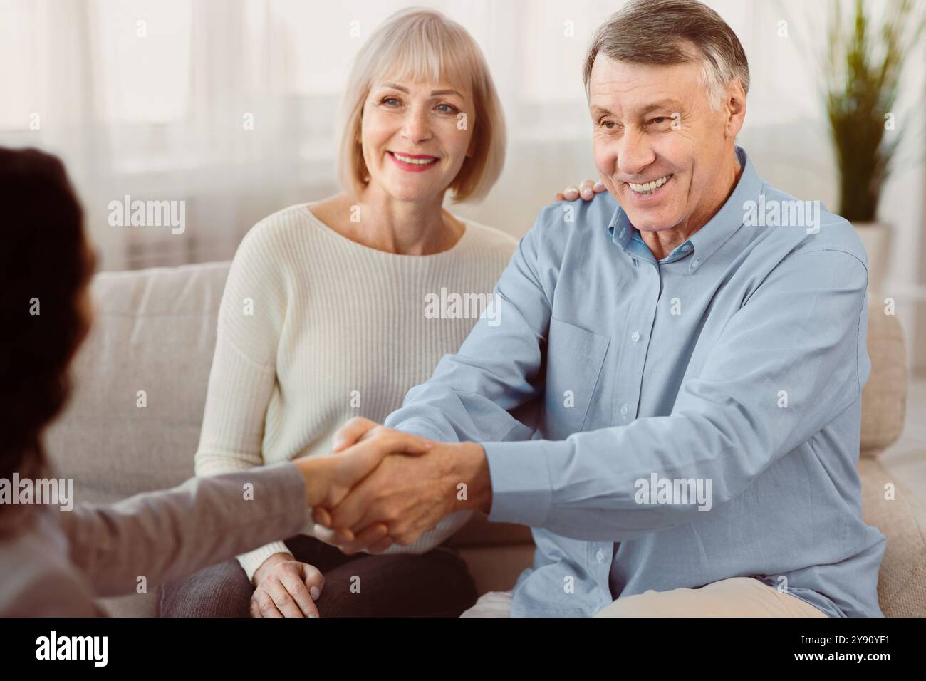 Glückliches reifes Paar, das dem Arzt einen Handschlag gibt Stockfoto