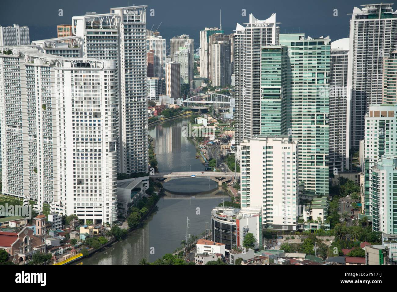 Die Hauptstadt ist hell beleuchtet, in der Nähe des Sonnenuntergangs, im Kontrast zu einem dunklen Himmel, wenn sich Regen nähert. Der beleuchtete Pasig River fließt durch die riesige Metropole, zwischen A Stockfoto