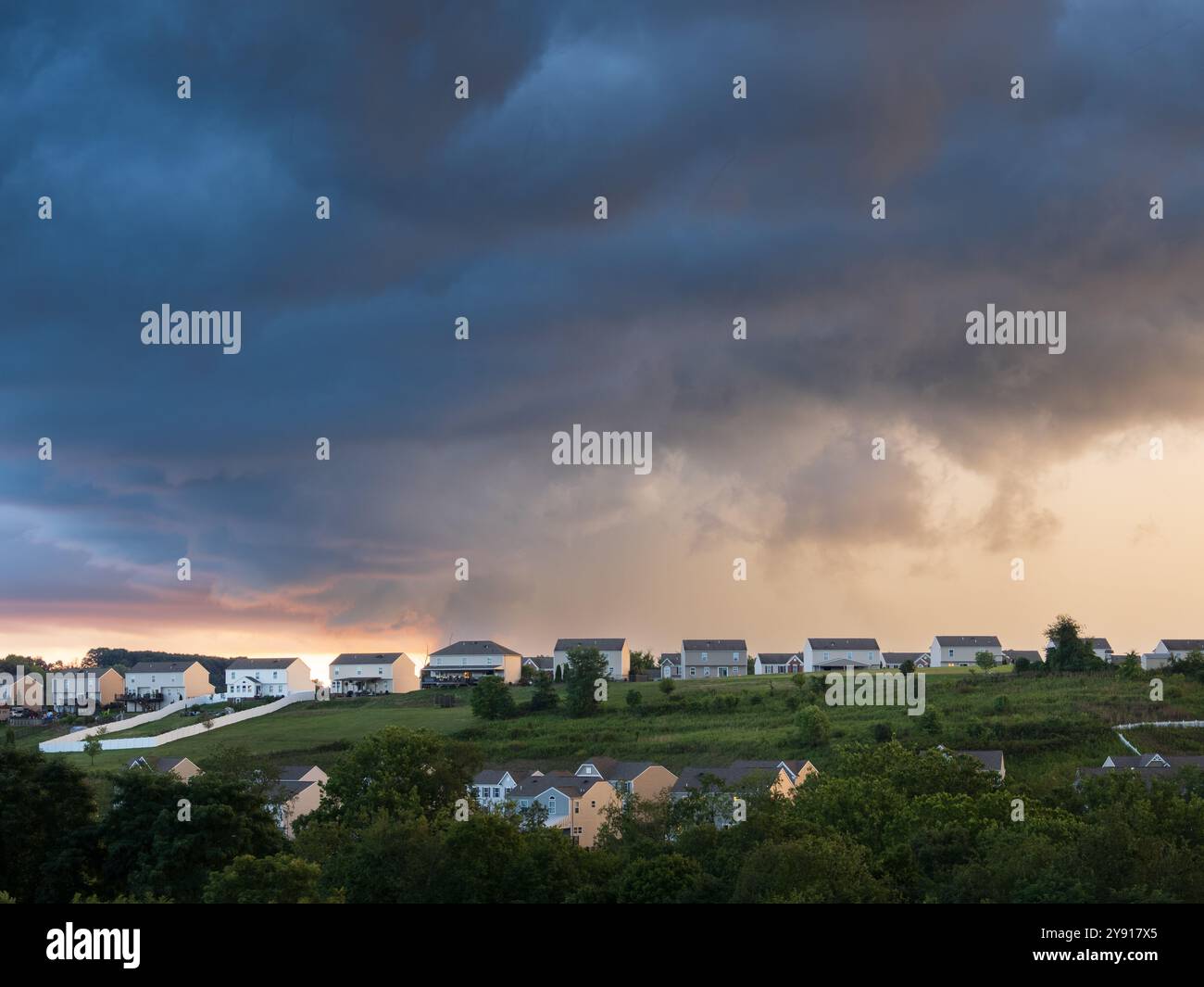 Sturmwolken erheben sich über einem friedlichen Viertel der USA, und ein heller Bruch im Himmel bietet einen Blick auf Hoffnung an einem Sommerabend. Stockfoto