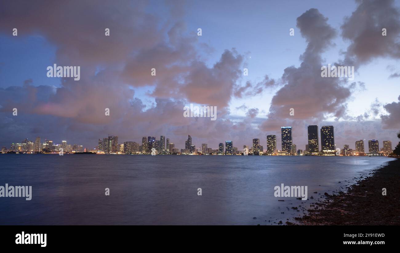 Rosa Licht aus Wolken aus dem Sonnenuntergang über der Innenstadt Skyline von Miami hinter dem Atlantik widerspiegelt Stockfoto