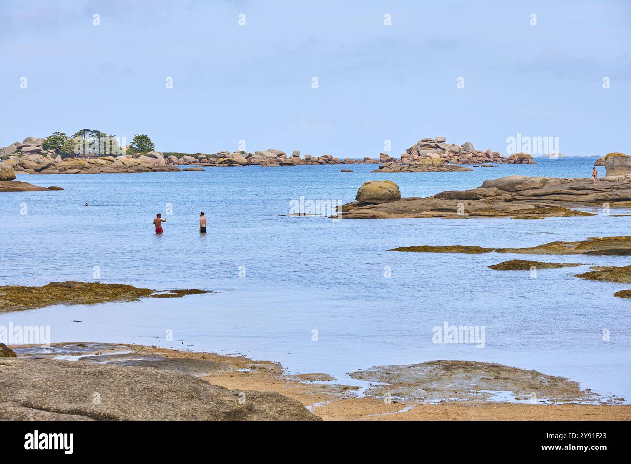 Plage de Tourony, Tournoy Beach, Cote de Granit Rose, Bretagne, Frankreich, heller Sand und Badegäste am Strand bei ruhigem Wetter. Runder Granit r Stockfoto