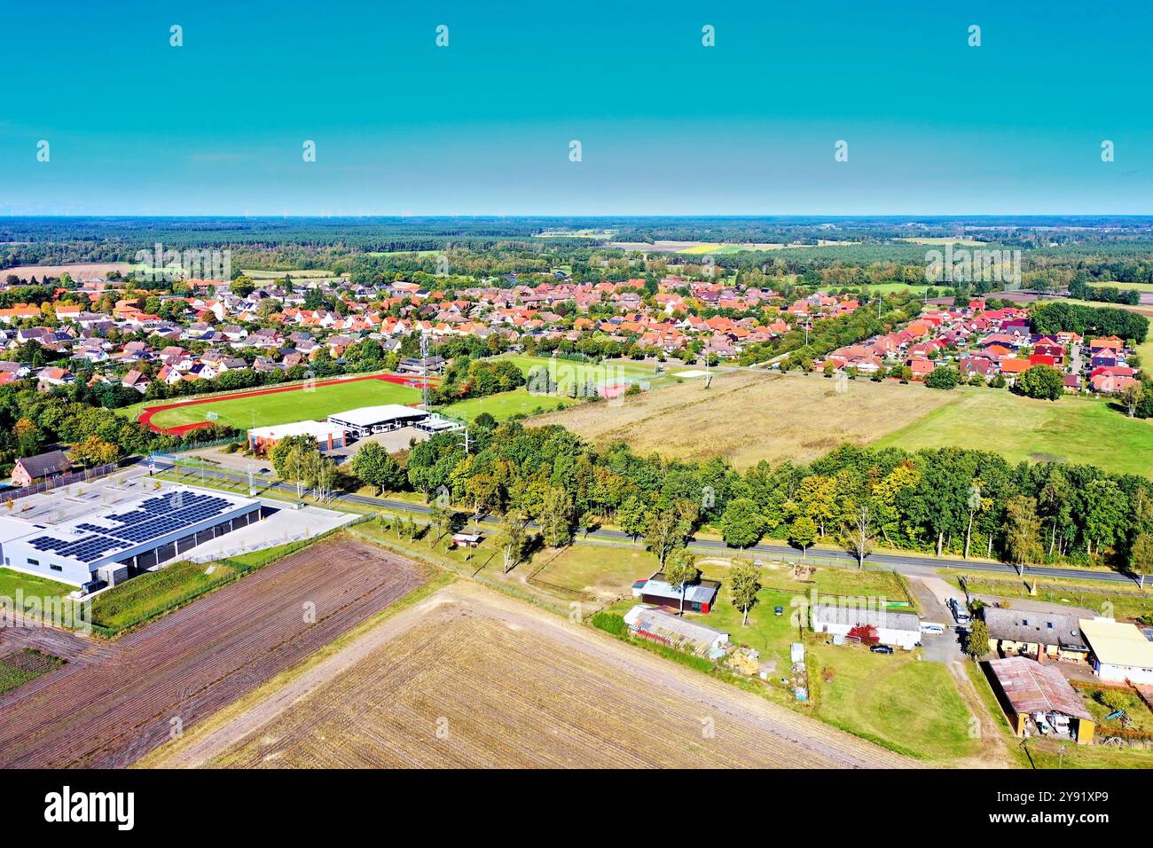 Luftaufnahme eines kleinen Dorfes in deutschland, mit Häusern, einem Sportplatz, landwirtschaftlichen Feldern und einem Wald im Hintergrund Stockfoto