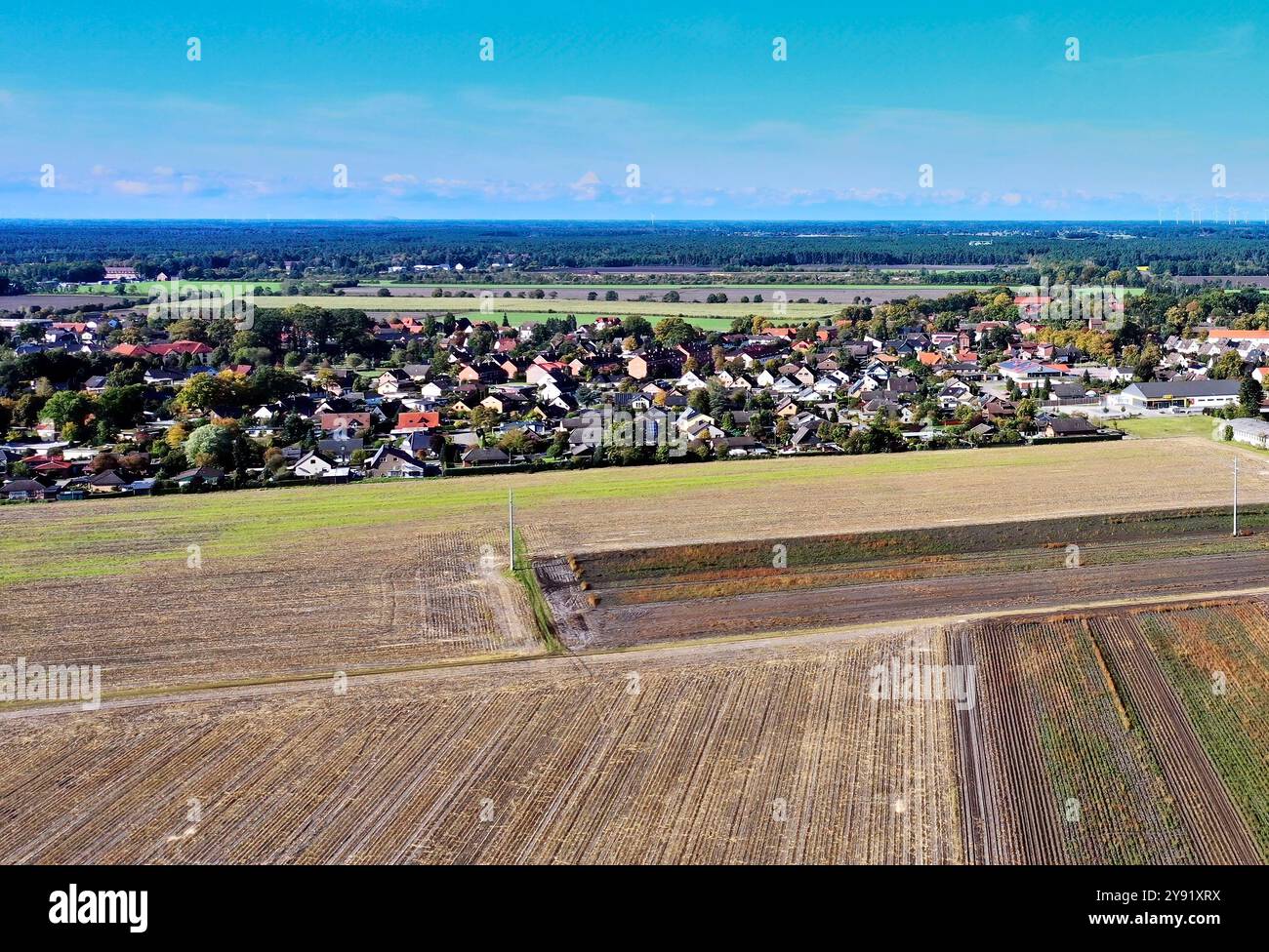 Luftaufnahme einer kleinen Stadt in deutschland mit landwirtschaftlichen Feldern und einem Wald im Hintergrund an einem sonnigen Tag mit wenigen Wolken Stockfoto