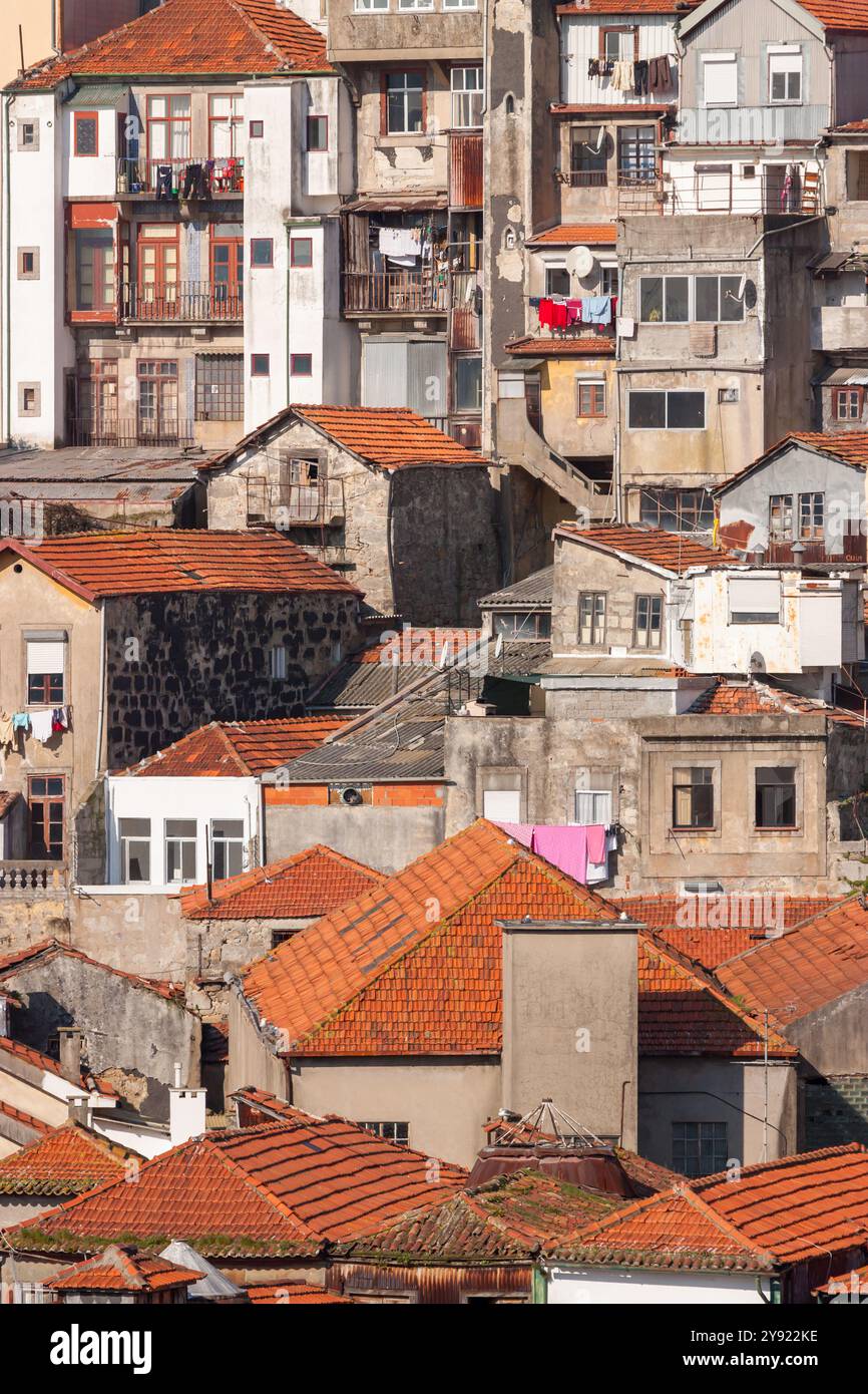 Ein rauer und rauer Blick auf die Stadt Porto mit alten alten Gebäuden, orangefarbenen Dächern und grauen Wänden. Ein vertikales Foto. Stockfoto