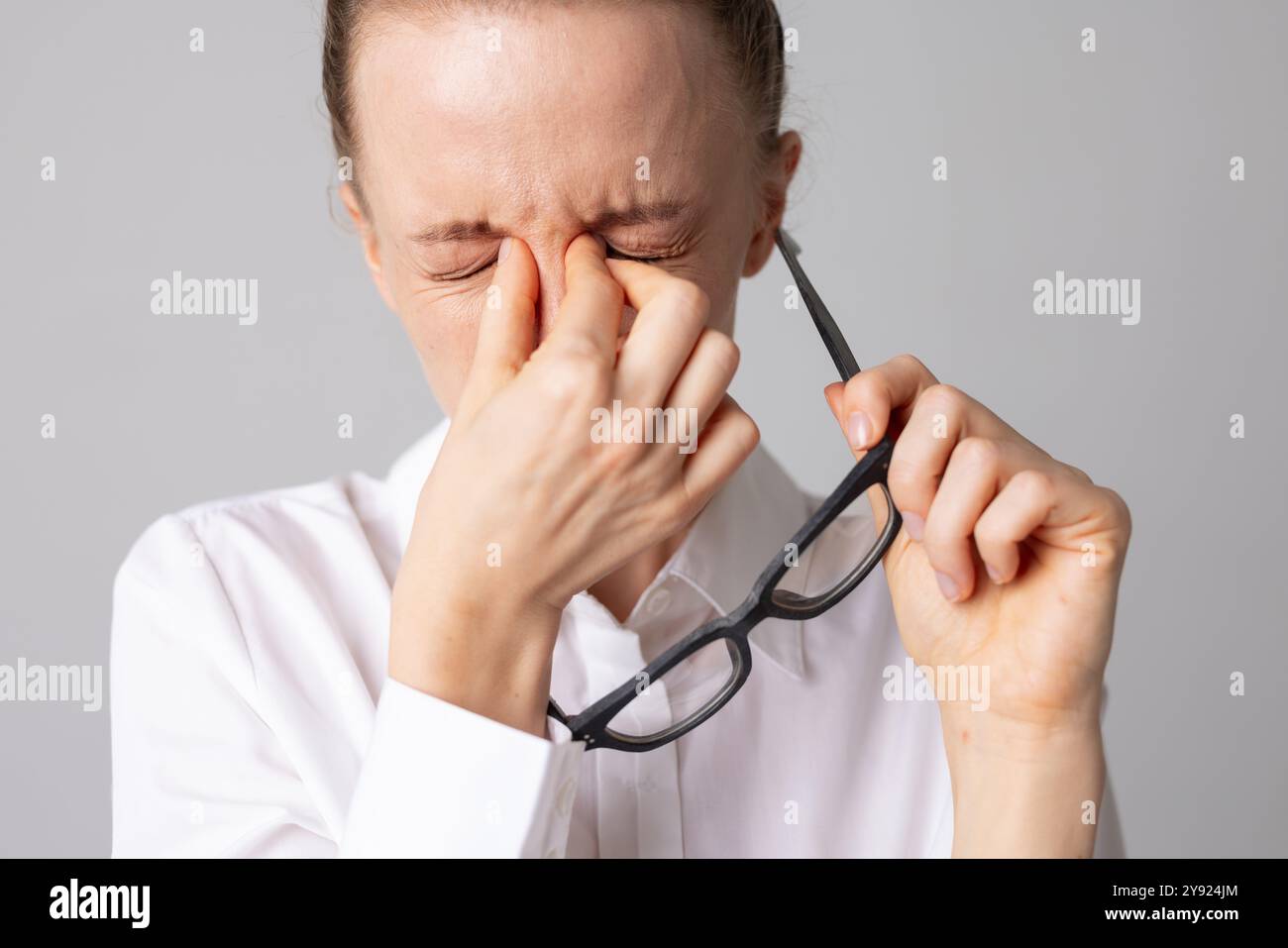 Frau zieht ihre Brille ab und hält ihre Augen vor Schmerzen, Konzept der Optik, Brillenauswahl und Sehstörungen Stockfoto