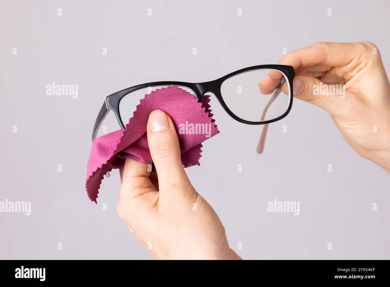 Frau, die die Brille mit einem speziellen Tuch abwischt, Konzept des guten Sehens, Brillenauswahl, Brillenpflege Stockfoto