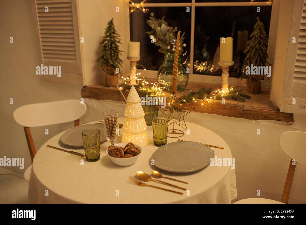 Gemütliches Weihnachtsgesang mit einem runden Tisch in der Nähe des Fensters, der Tisch ist mit einem dekorativen Weihnachtsbaum in der Mitte dekoriert, sanfte Beleuchtung von c Stockfoto