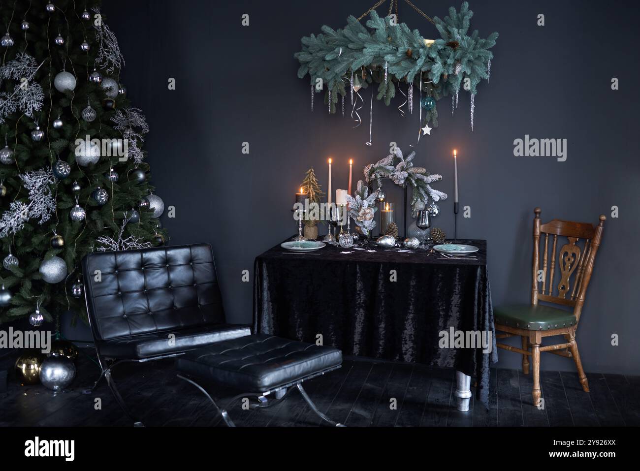Stilvolles Silvester-Interieur in dunklem Stil, Neujahrsbaum mit Neujahrsspielzeug und dekoriertem Tisch im dunklen Stil Stockfoto