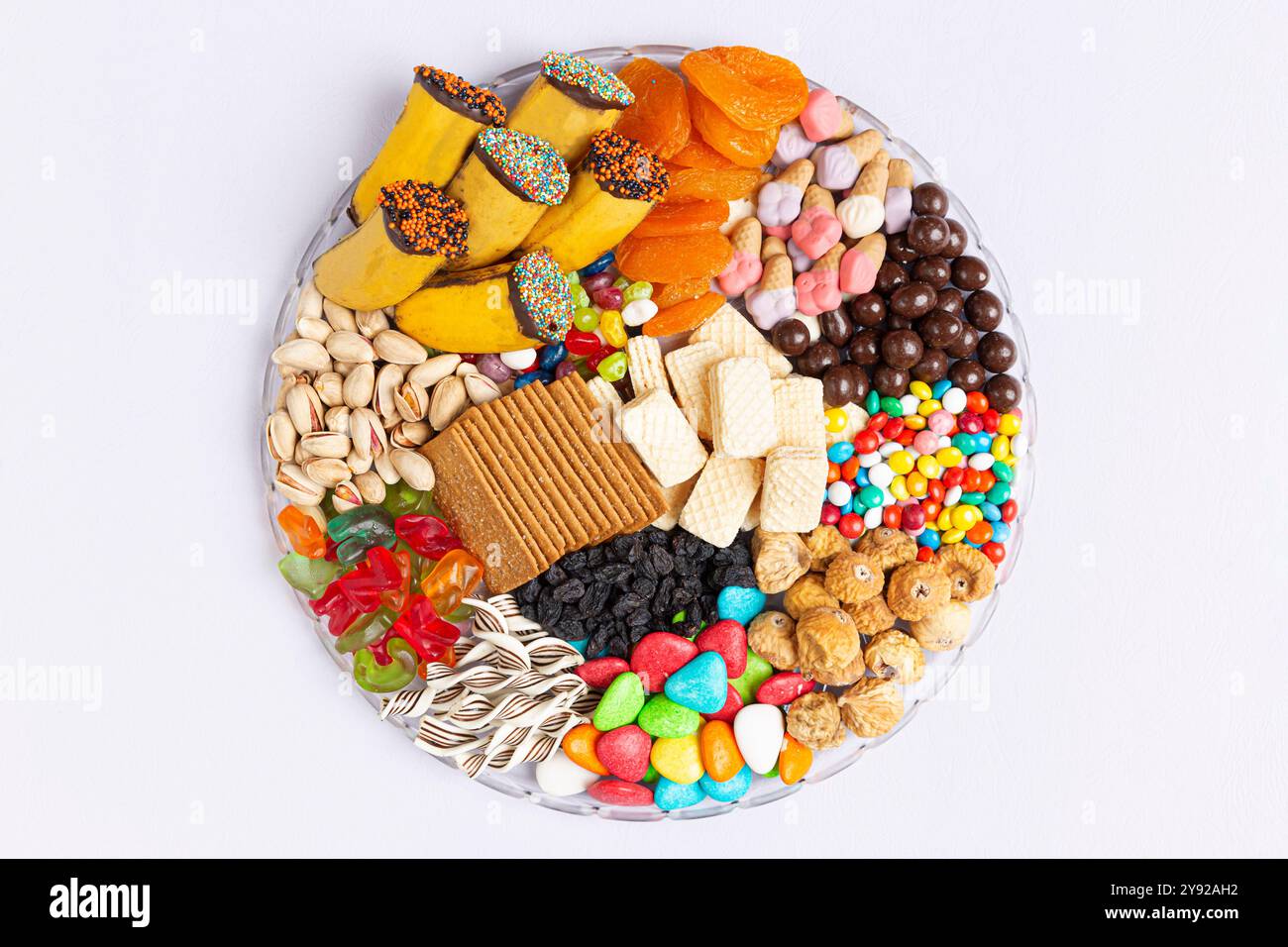 Verschiedene Snacks und Leckereien auf einer lebendigen Platte, einschließlich Kekse, getrocknetes Obst, Nüsse und Süßigkeiten. Stockfoto