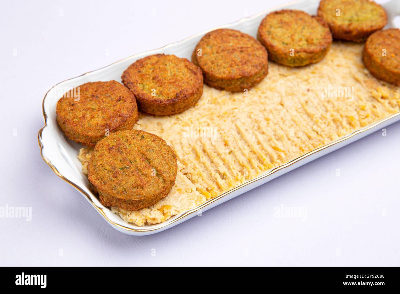 Knusprige Falafel-Patties auf einem glatten Hummus-Bett auf einem weißen Teller, nahöstliche Küche aus nächster Nähe Stockfoto