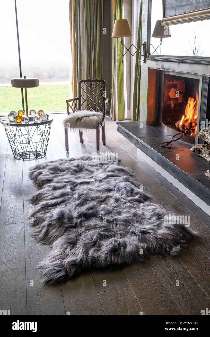 Beleuchtetes Feuer mit Lammfellteppich von Wildash, nachhaltig finanzierte luxuriöse Wohnmöbel, London. Stockfoto