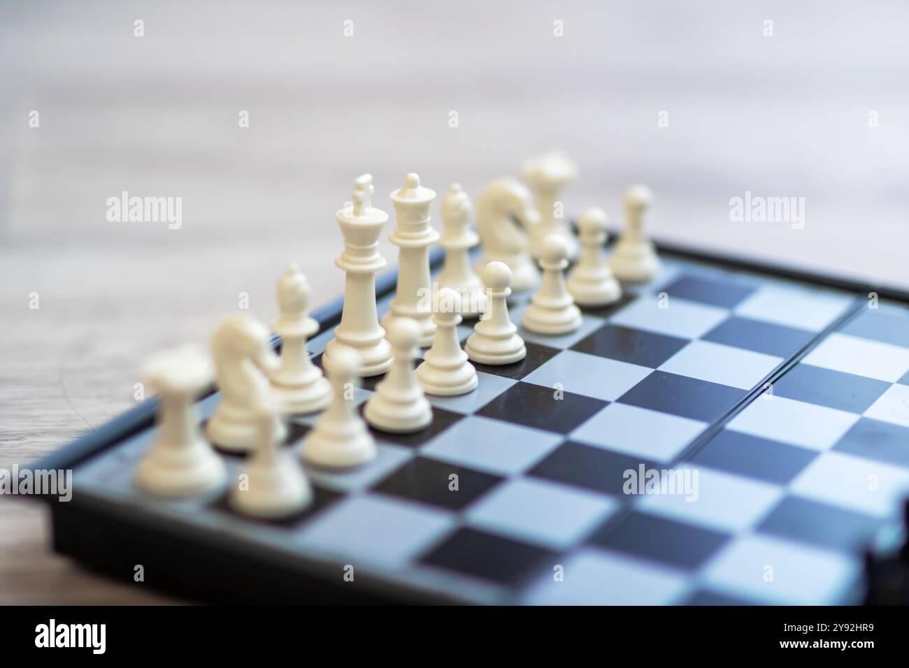 Eine detaillierte Nahaufnahme eines Schachbretts mit weißen und schwarzen Teilen, die strategisch darauf platziert sind, zeigt das komplizierte Design der Spiele Stockfoto