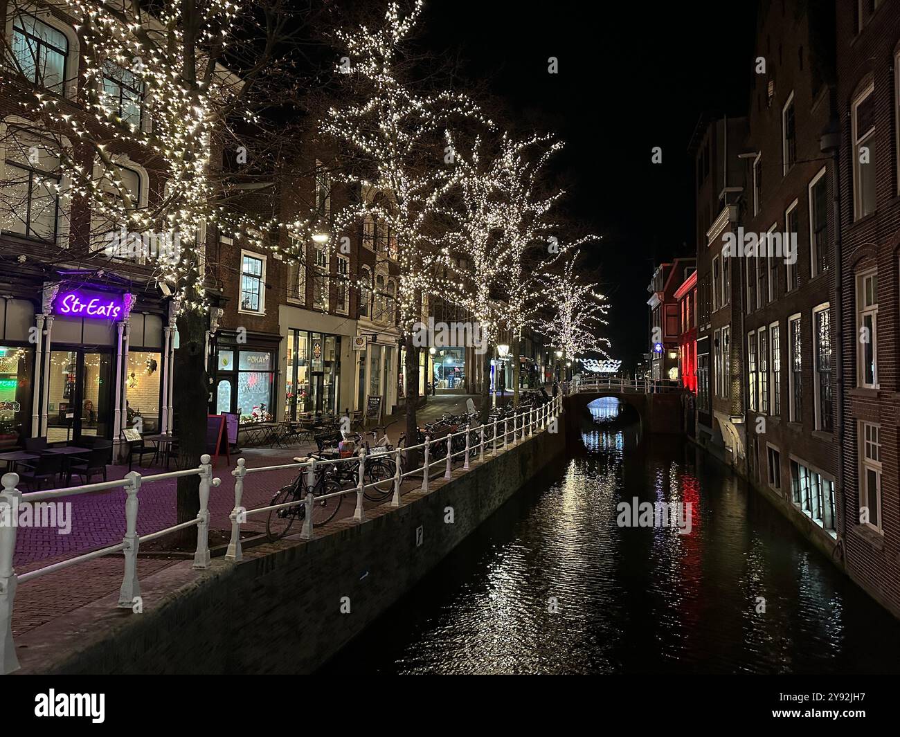 Delft, Niederlande: 17. Dezember 2023: Wijnhaven und der Nieuwe-Delfter Kanal bei Nacht mit Weihnachtslichtern in den Bäumen - Smartphone-aufgenommenes Stockfoto