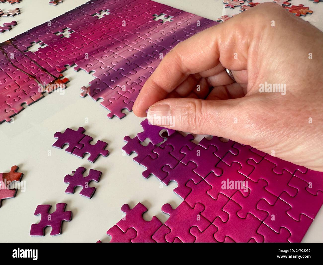 Ein Puzzle aus nächster Nähe mit Hand- und Puzzleteilen Stockfoto